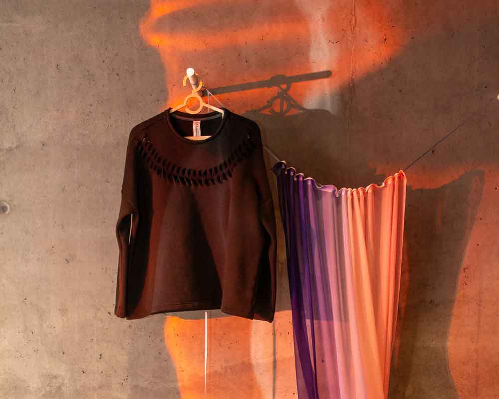 Asmuss Anni Sweatshirt hanging alongside an Alicia Fanckovich artwork that includes a chiffon curtain in pink and purple