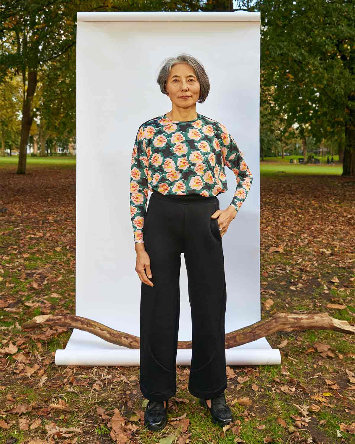 Woman standing, front on, with a hand on her hip in front of a white background, weighted down by a branch. She is wearing the Asmuss Column Joggers and Asmuss Paige Long Sleeve T-shirt.