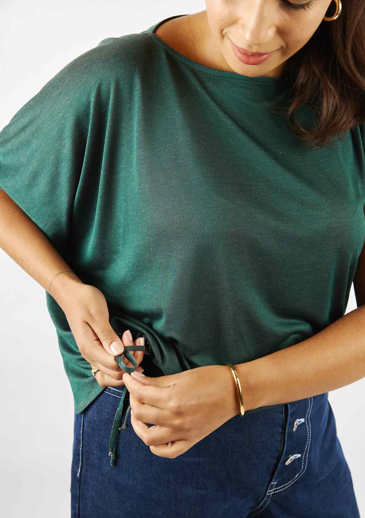 Woman wearing the Asmuss Head Tshirt and tightening the self fabric drawstring to personalise the shape of the tshirt