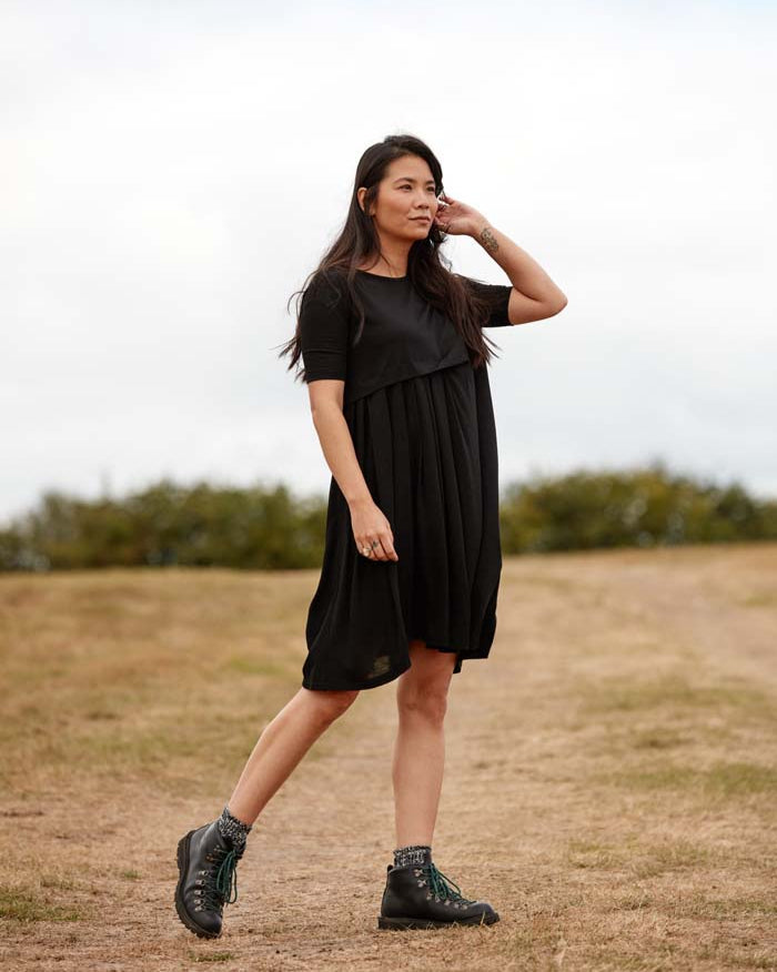 Woman wearing the Asmuss Asymmetric Pleat Dress in Black for a countryside walk. Look stylish while being functional and comfortable an ideal everyday essential that has built in temperature regulating 37.5 Technology.