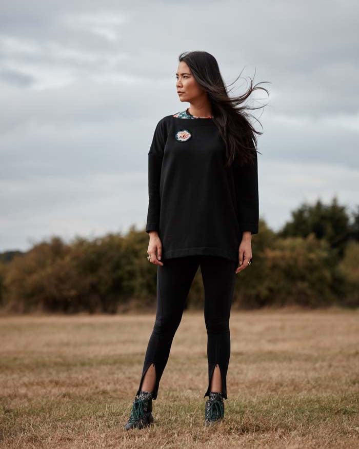Woman wearing the Asmuss Oversized Boat Neck Sweat with embroidered rose badge. The perfect elevated sweatshirt to throw on over practically anything including activewear for all of your everyday adventures..