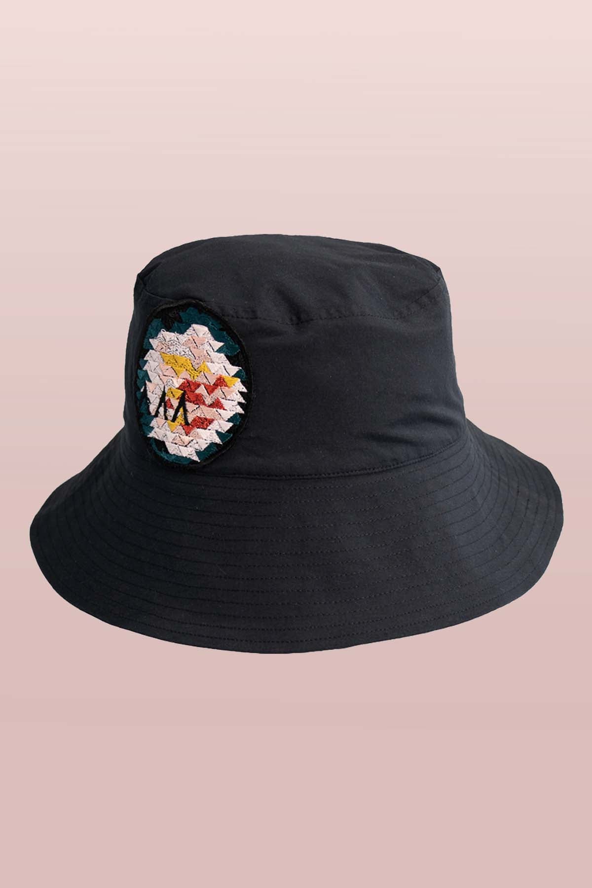 Front view of the Asmuss Wide Brim Bucket Hat in black with rose embroidery badge. The perfect sun hat to keep the sun off your face but still look good and with water resistance to keep the rain off too.