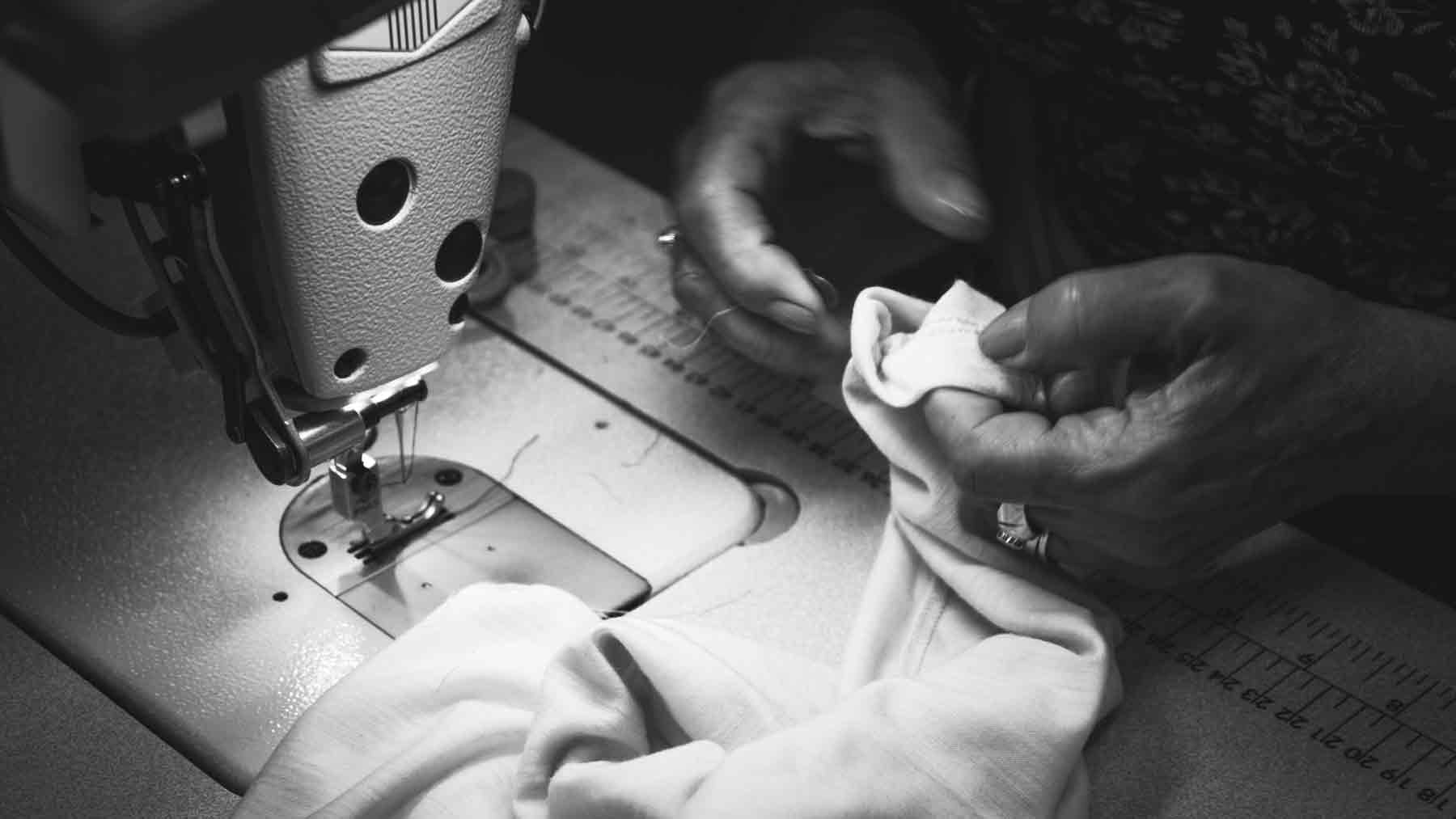 Hands of a women snipping threads at her sewing machine making Asmuss clothing