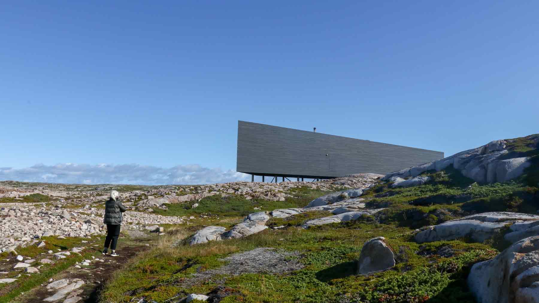 Side view of the Long Studio on Fogo Island with the mother of the Asmuss founders walking towards it