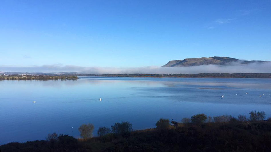 Loch Leven, Scotland, with clear blue sky and a line of mist in front of Bishops Hill
