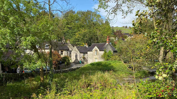 View of Milldale stone cottages across the river, Peak District