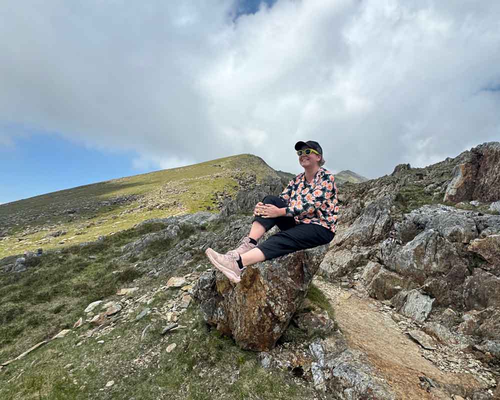 Clare taking a break sitting on a rock on a hike up Snowdon