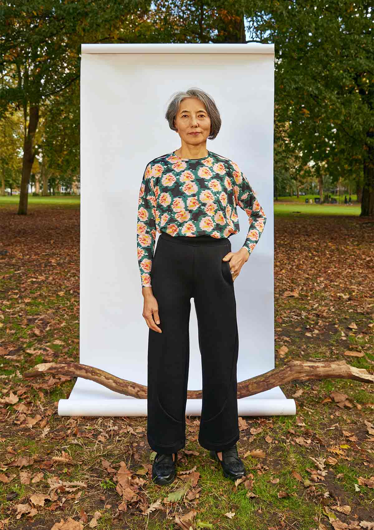 Woman standing, front on, with a hand on her hip in front of a white background, weighted down by a branch. She is wearing the Asmuss Column Joggers and Asmuss Paige Long Sleeve T-shirt.