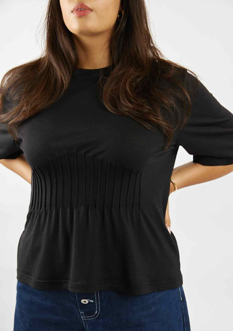 Woman with hands on her hips showing the pin tuck detail of the hand embellished black tshirt
