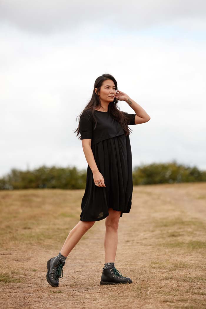 Woman wearing the Asmuss Asymmetric Pleat Dress in Black for a countryside walk. Look stylish while being functional and comfortable an ideal everyday essential that has built in temperature regulating 37.5 Technology.