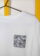 Close up of white Evelyn tee-shirt showing the black hand embroidery of an outline of a cluster of roses within a square, placed on chest at left hand side of tee-shirt