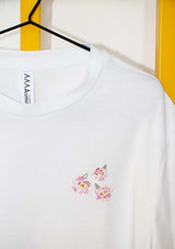 Close up of white Evelyn tee-shirt showing hand embroidery of 3 geometric roses in pinks, mustard and green. Placed on chest at left hand side of tee-shirt 